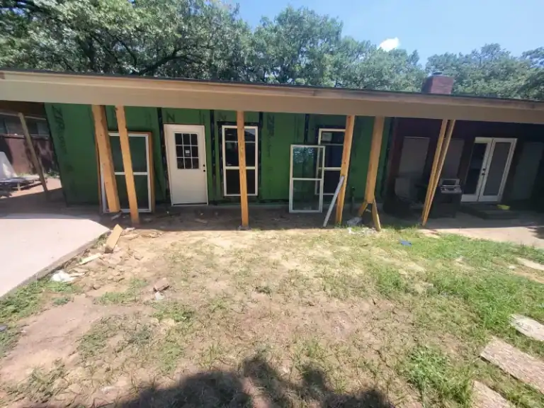 Back patio perspective with porch posts, framed door, and window openings ready for installation.