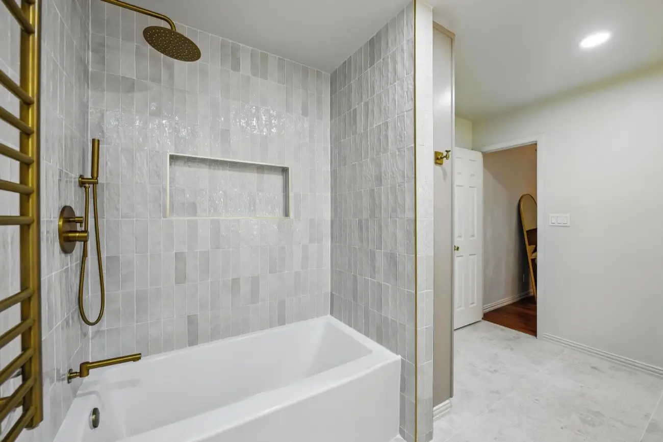 Tub & shower — vertical tile, recessed niche & brushed-gold fixtures · Colleyville