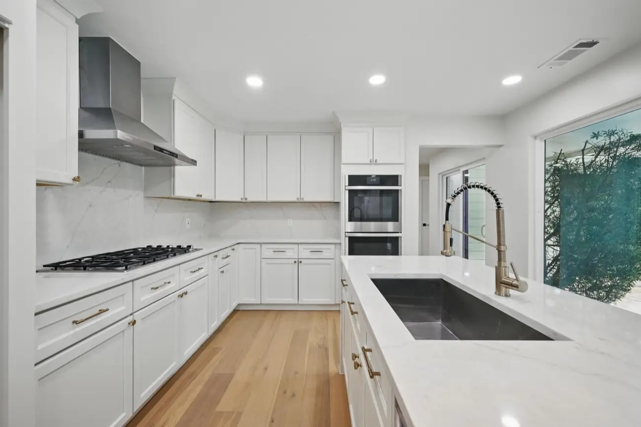 Open-concept kitchen — waterfall island, custom cabinets & gold fixtures · Dallas