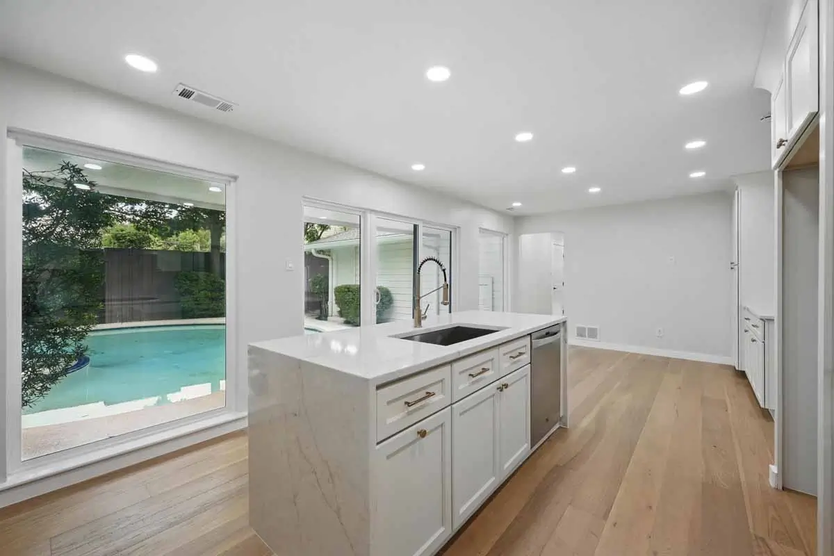Remodeled Kitchen Island Beside Large Windows Overlooking The Backyard Pool 010