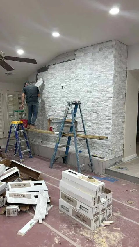 Worker Installing White Stone Around The Remodeled Living Room Fireplace 054